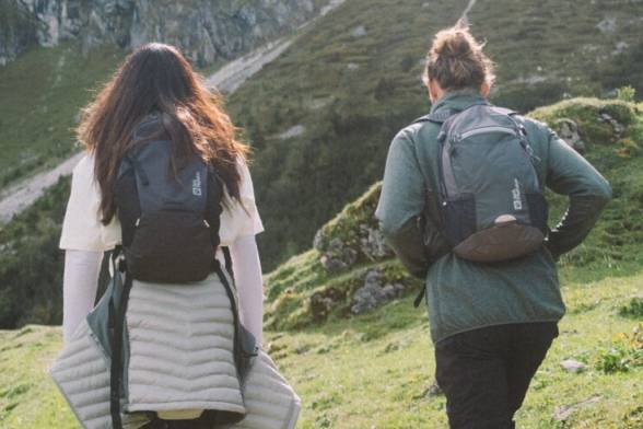 Summery shot of two hikers with hiking rucksacks in a sporty look from behind